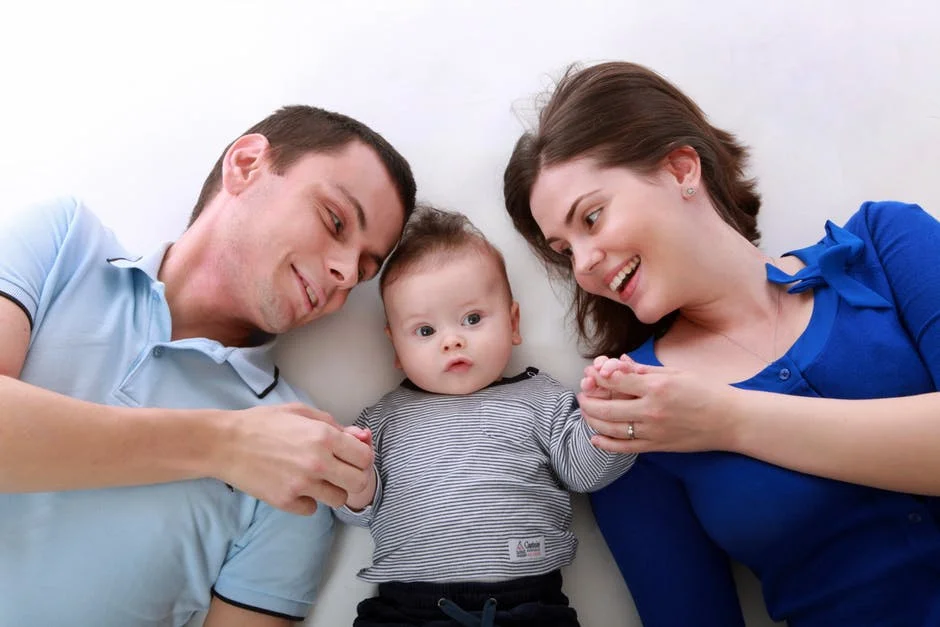 Two parents lying beside their baby